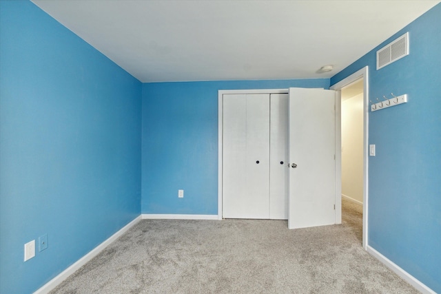 unfurnished bedroom with a closet and light colored carpet