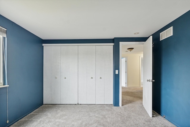 unfurnished bedroom with light colored carpet and a closet