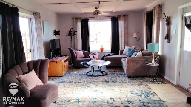 living room with ceiling fan, plenty of natural light, and coffered ceiling