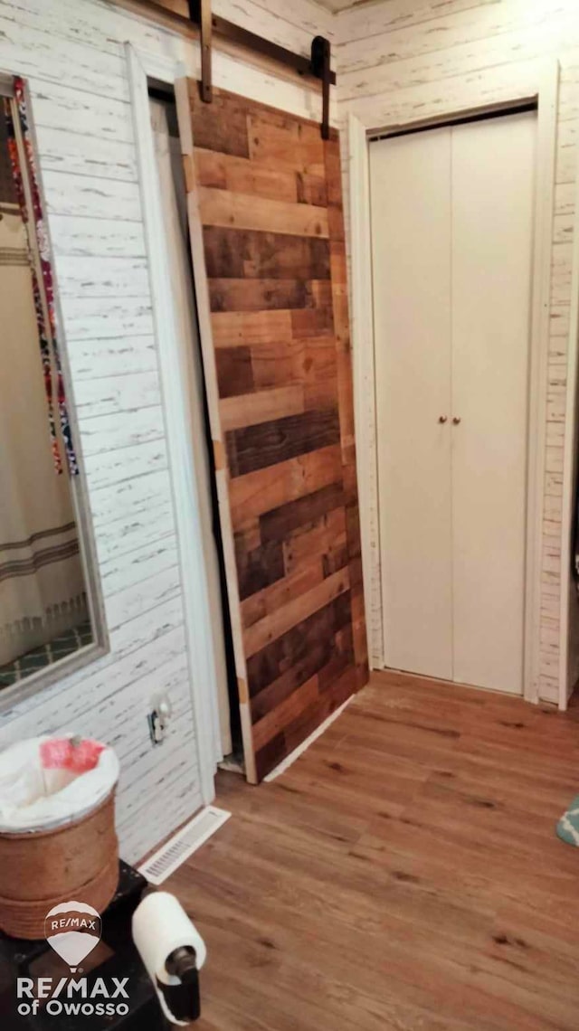 interior space featuring a barn door, wood walls, and wood-type flooring