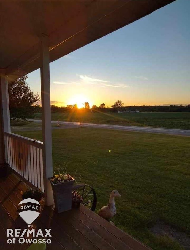 deck at dusk with a yard and a rural view