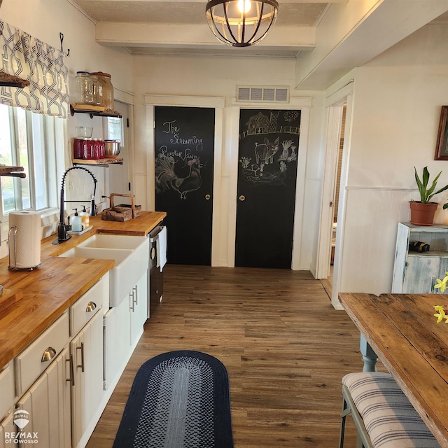 kitchen featuring white cabinetry, dark hardwood / wood-style flooring, beamed ceiling, butcher block countertops, and decorative light fixtures