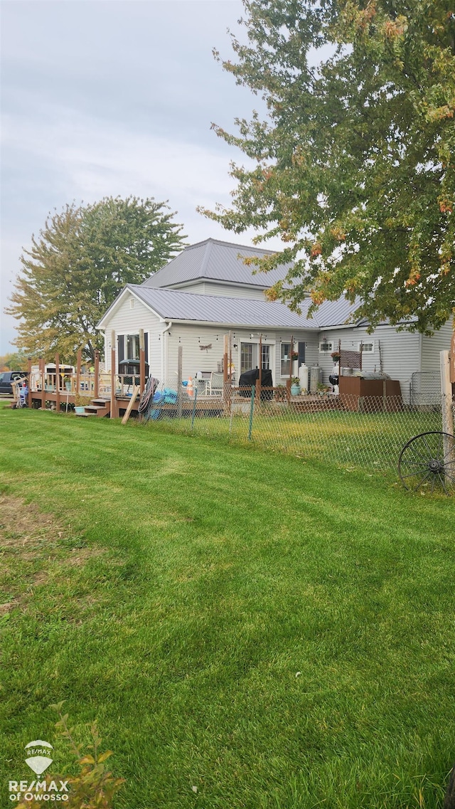 back of property with a lawn and a wooden deck