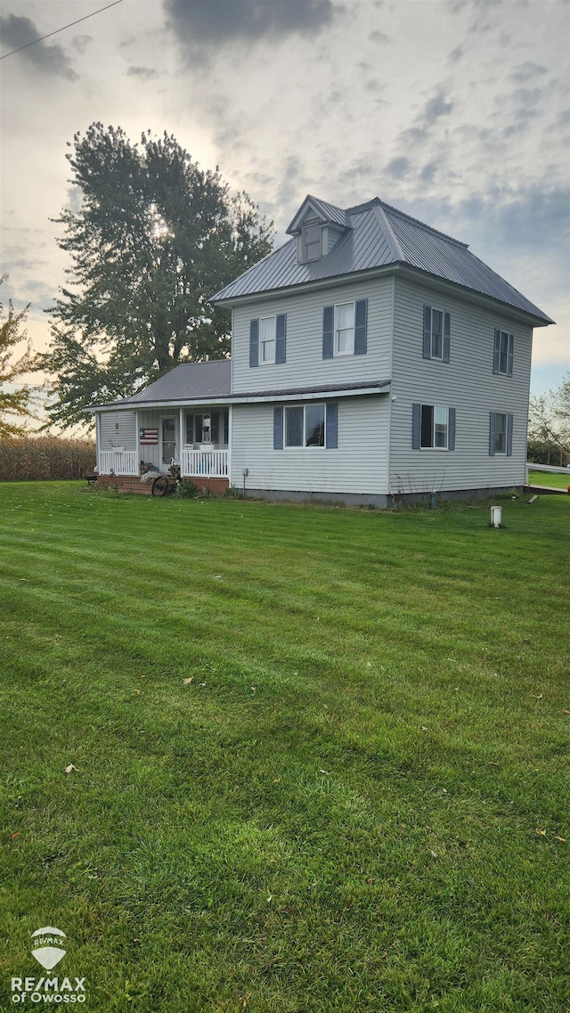 back house at dusk with a porch and a yard