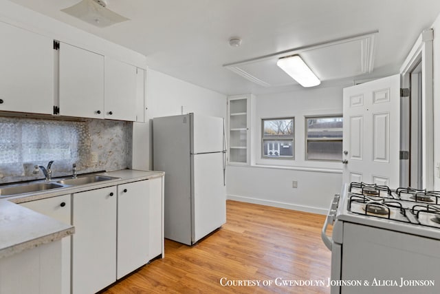 kitchen featuring sink, white cabinets, white appliances, and light wood-type flooring