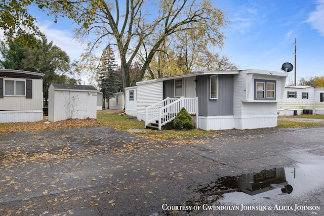 manufactured / mobile home with central air condition unit and a storage shed