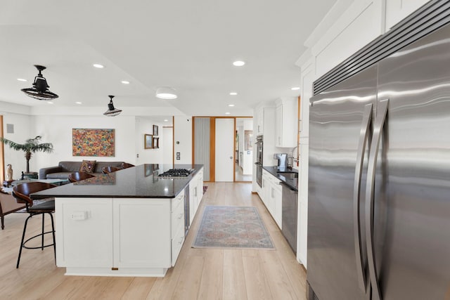 kitchen with a kitchen island, white cabinets, stainless steel appliances, and light wood-type flooring