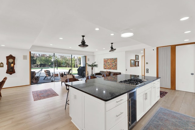 kitchen featuring wine cooler, light wood-type flooring, a center island, and white cabinetry