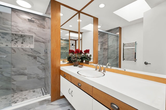 bathroom with vanity, a shower with door, and a skylight