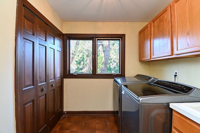 clothes washing area with cabinet space, dark tile patterned flooring, baseboards, and washing machine and dryer