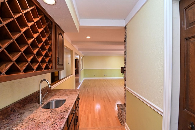 interior space featuring wet bar, a sink, baseboards, recessed lighting, and light wood-style flooring