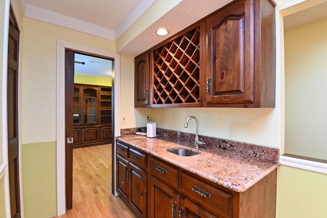 bar featuring wet bar, a sink, and light wood-style flooring