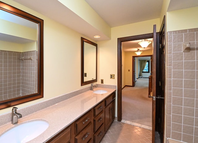 bathroom with double vanity, tile patterned floors, a tile shower, and a sink