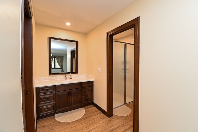 bathroom with vanity, recessed lighting, baseboards, wood finished floors, and a shower with door
