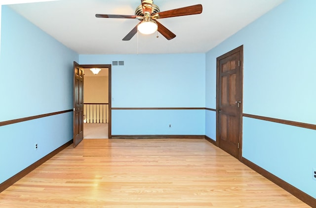 unfurnished room with baseboards, a ceiling fan, light wood-type flooring, and visible vents