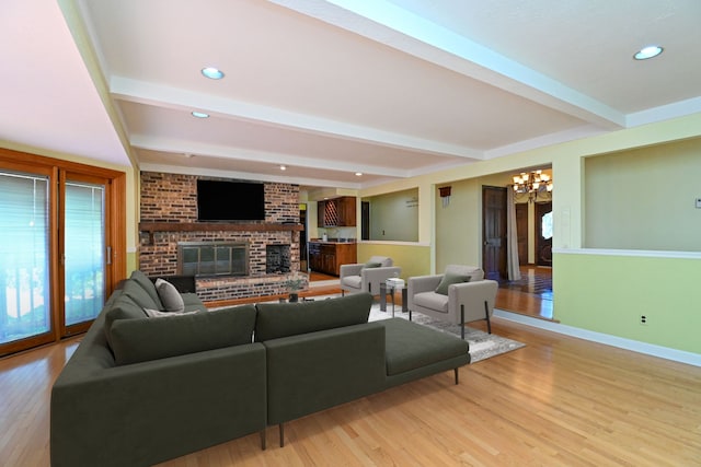 living room with a brick fireplace, a chandelier, beam ceiling, and light hardwood / wood-style flooring