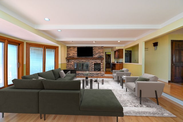 living room featuring a brick fireplace, a wealth of natural light, beam ceiling, and light hardwood / wood-style floors