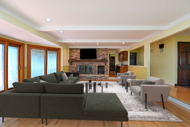 living area featuring a fireplace, beamed ceiling, baseboards, light wood-type flooring, and recessed lighting