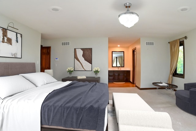 bedroom with a sink, light carpet, connected bathroom, and visible vents