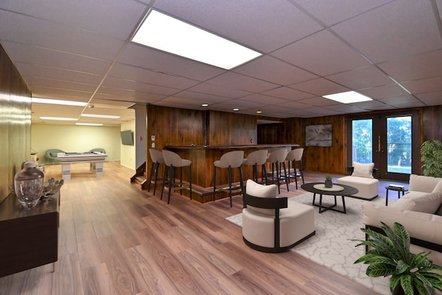 living area with a dry bar, wood walls, wood finished floors, and a paneled ceiling
