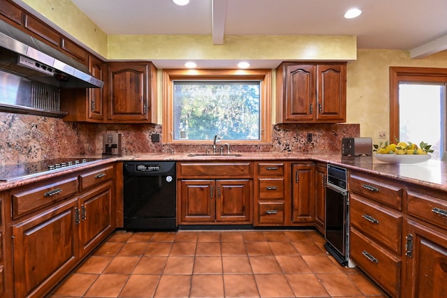 kitchen featuring a sink, a healthy amount of sunlight, tasteful backsplash, under cabinet range hood, and black appliances