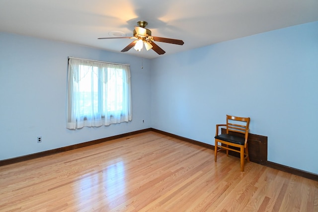 empty room with light wood-style floors, a ceiling fan, and baseboards