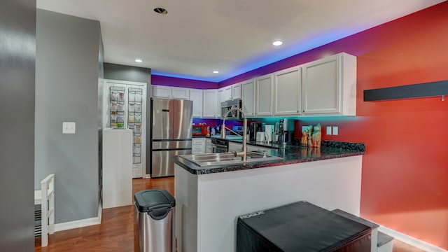 kitchen featuring white cabinets, dark hardwood / wood-style floors, kitchen peninsula, and appliances with stainless steel finishes