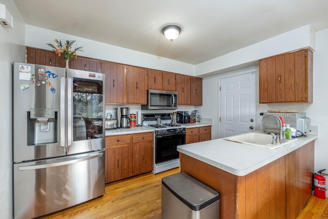 kitchen featuring kitchen peninsula, sink, stainless steel appliances, and light wood-type flooring