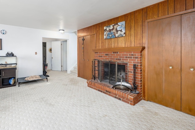 living room featuring wood walls, light carpet, and a brick fireplace