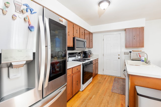 kitchen with sink, stainless steel appliances, and light wood-type flooring