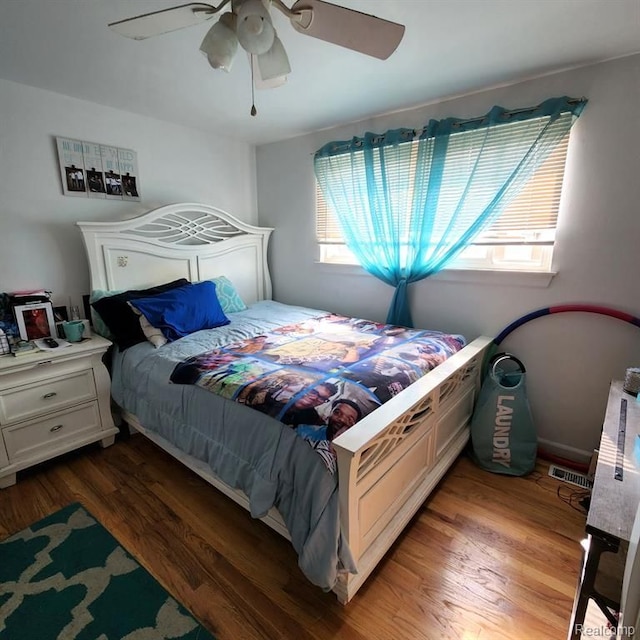 bedroom with ceiling fan, dark hardwood / wood-style flooring, and multiple windows