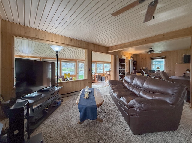 carpeted living room featuring ceiling fan and wood walls