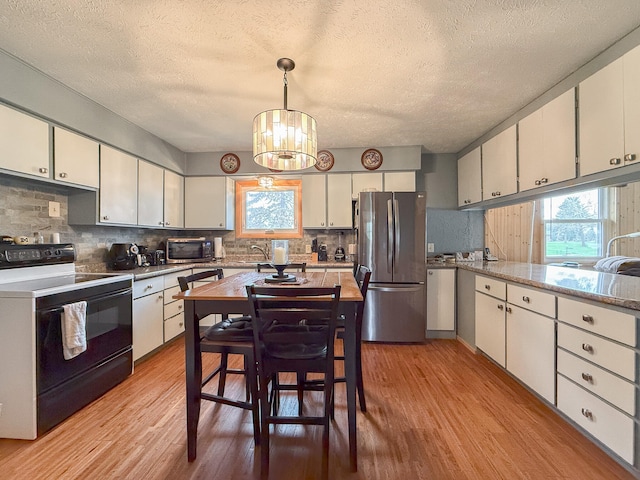 kitchen featuring a textured ceiling, decorative light fixtures, light wood-type flooring, and stainless steel appliances