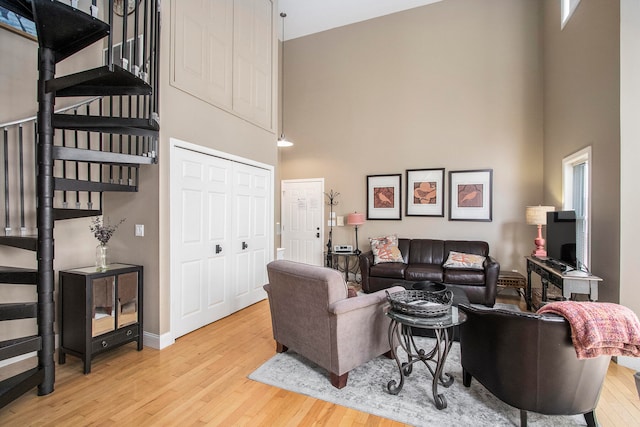 living room with a towering ceiling, light hardwood / wood-style floors, and a wealth of natural light