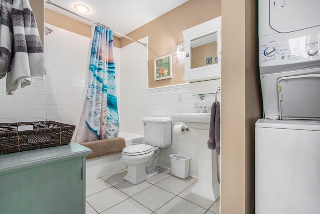 bathroom with shower / bathtub combination with curtain, stacked washing maching and dryer, tile patterned floors, toilet, and tile walls