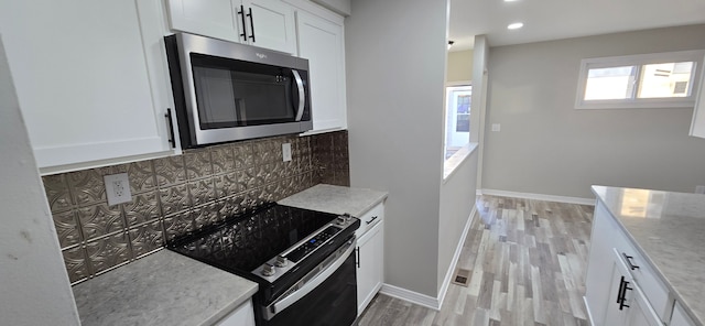 kitchen featuring decorative backsplash, white cabinetry, light hardwood / wood-style flooring, and stainless steel appliances