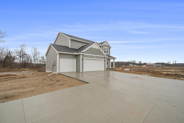 view of side of property with an attached garage, concrete driveway, and roof with shingles