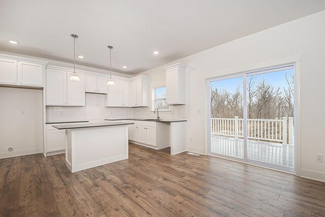 kitchen featuring a center island, white cabinetry, dark wood finished floors, and backsplash