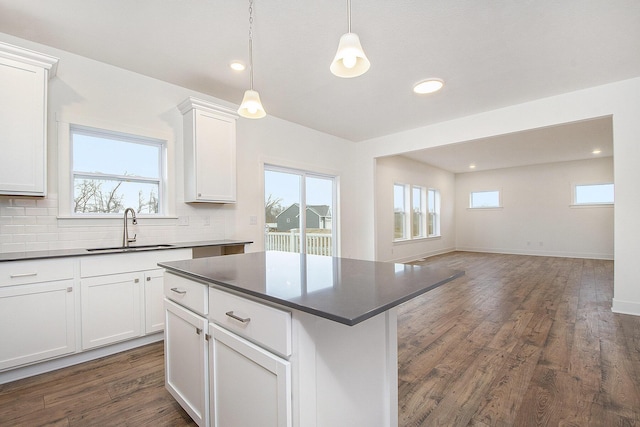 kitchen with dark wood-style floors, tasteful backsplash, dark countertops, and a sink