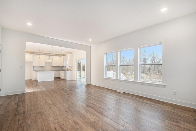 unfurnished living room with recessed lighting, visible vents, baseboards, and wood finished floors