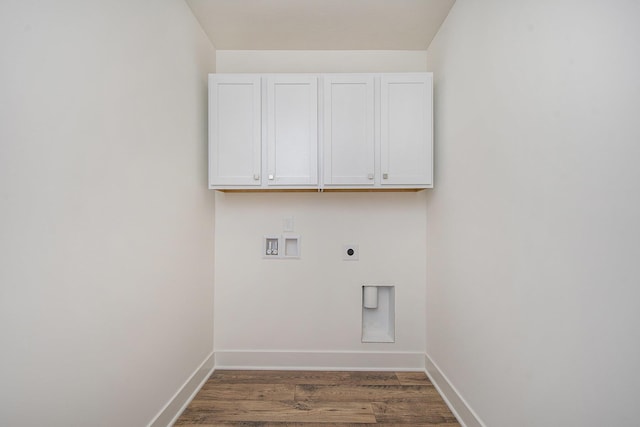 clothes washing area featuring washer hookup, cabinet space, electric dryer hookup, wood finished floors, and baseboards