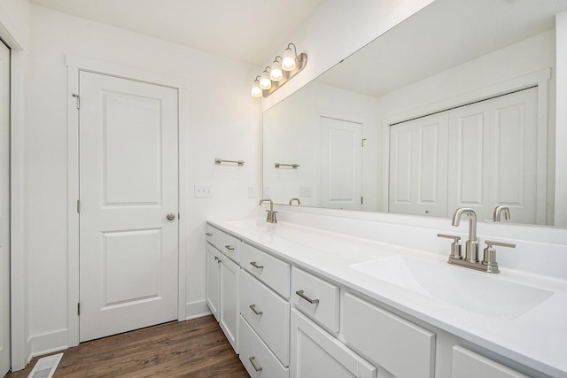 full bath with double vanity, wood finished floors, a sink, and visible vents