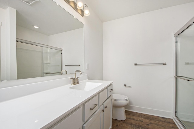 bathroom featuring toilet, wood finished floors, vanity, baseboards, and a stall shower