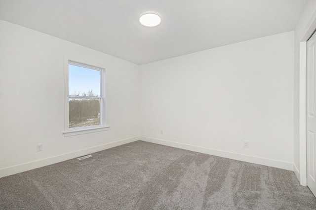 empty room featuring carpet flooring, visible vents, and baseboards