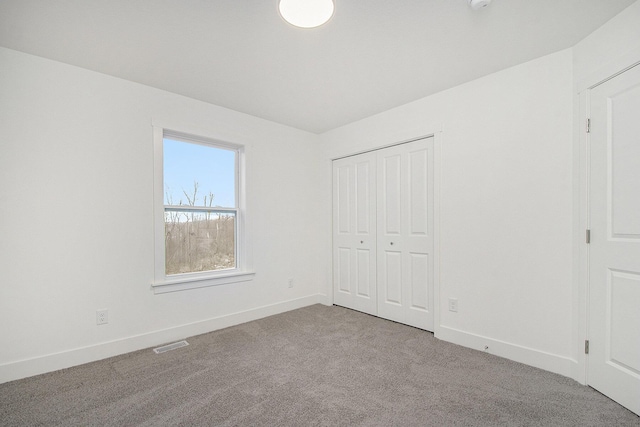 unfurnished bedroom featuring carpet floors, a closet, visible vents, and baseboards