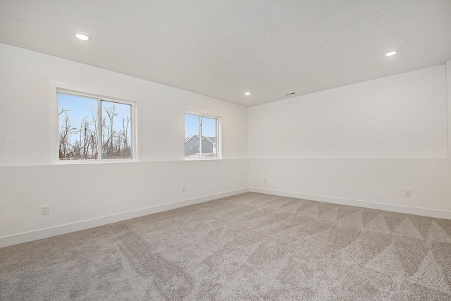 spare room with recessed lighting, baseboards, and light colored carpet
