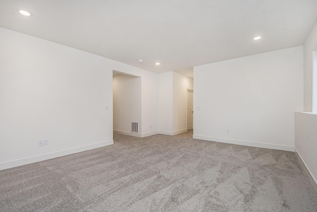 spare room featuring light colored carpet, recessed lighting, visible vents, and baseboards