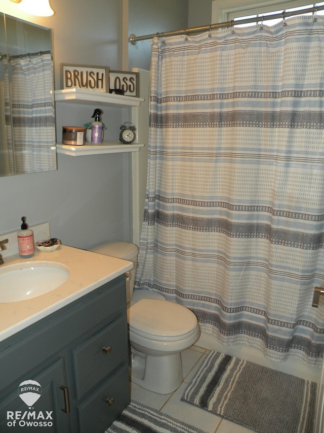 bathroom featuring tile patterned flooring, vanity, toilet, and walk in shower