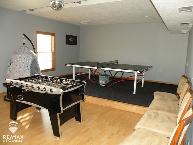 recreation room featuring wood-type flooring and a textured ceiling