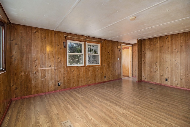 unfurnished room featuring wood walls and light hardwood / wood-style floors